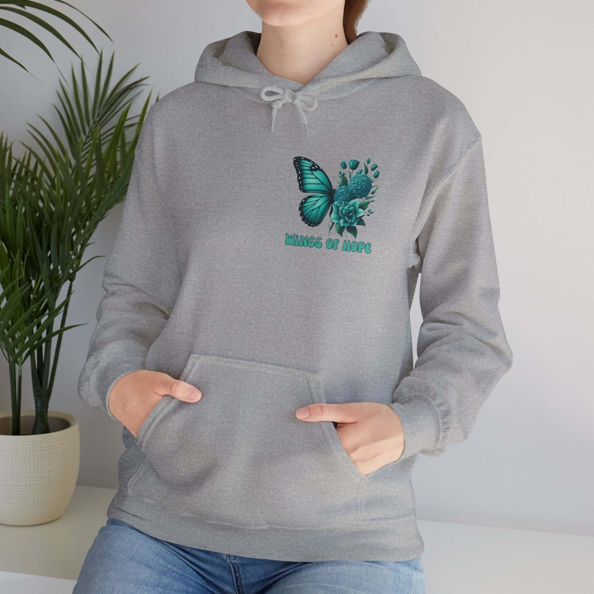 Woman wearing "Wings Of Hope" Butterfly and Flowers Hoodie in cozy indoor setting.