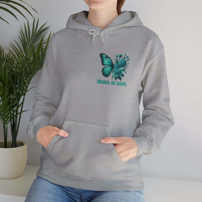 Woman wearing "Wings Of Hope" Butterfly and Flowers Hoodie in cozy indoor setting.